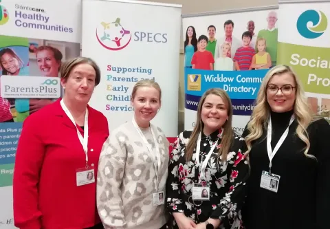 Four SPECS Bray female staff members standing in front of SPECS, Sláintecare and Wicklow Community Directory banners.