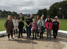 Group in People's Park standing holding large Green Ribbon